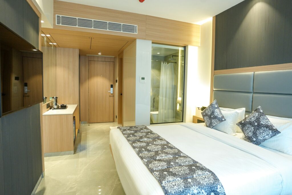 Hotel guest room with a bed and visible bathroom area, illustrating why hotels should provide precise room-specific measurements before booking.